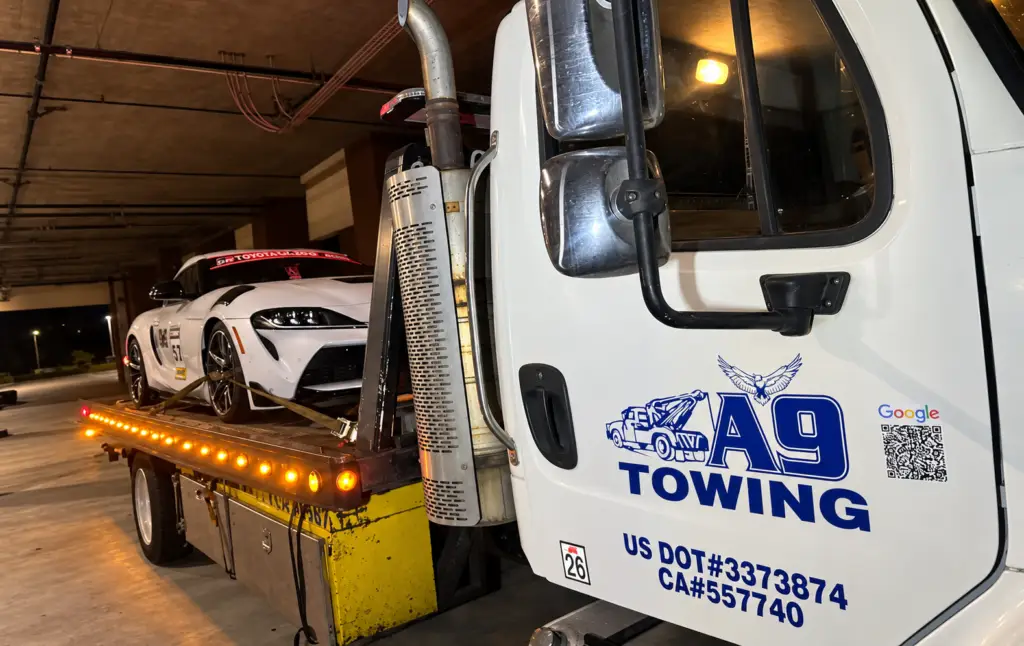 Tow truck at night carrying a sports car on the flatbed