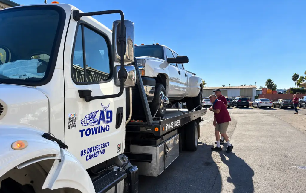 Tow truck loading a dually pickup truck in an industrial lot